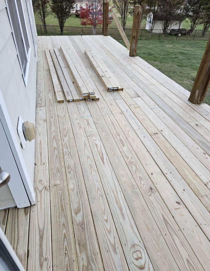 Newly built pressure-treated wood deck with framing lumber staged on the surface