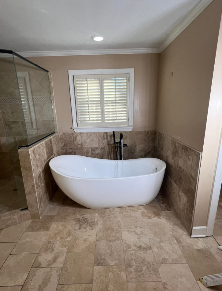 Remodeled bathroom with freestanding soaking tub, travertine tile wainscot and tile floor