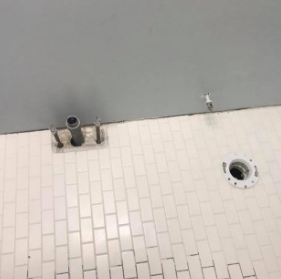 New white subway tile bathroom floor set around rough plumbing before fixtures