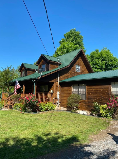 Log home with green metal roof and covered front porch