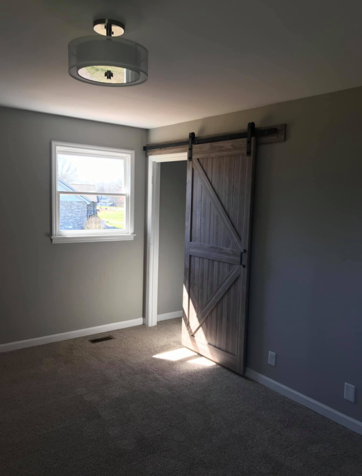 Remodeled bedroom with sliding barn door, new carpet, paint and ceiling light