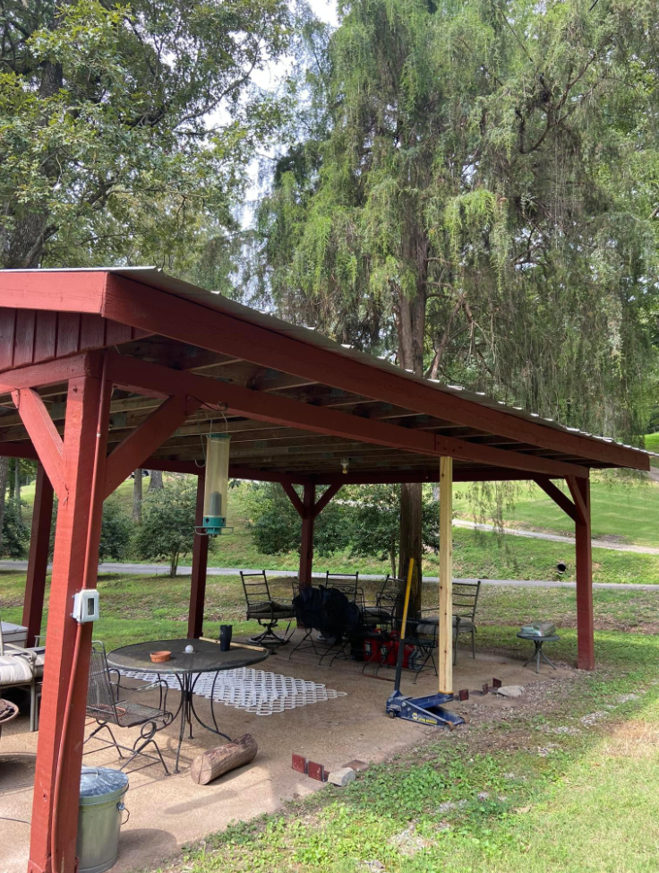 Red timber-framed backyard pavilion with metal roof