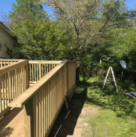Long elevated pressure treated deck and railing running along the side of a home