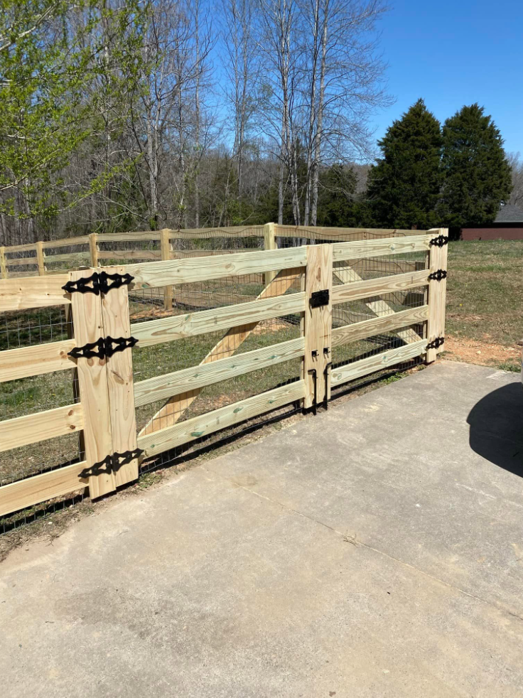 New four-board wood fence with wire mesh and black hardware gate